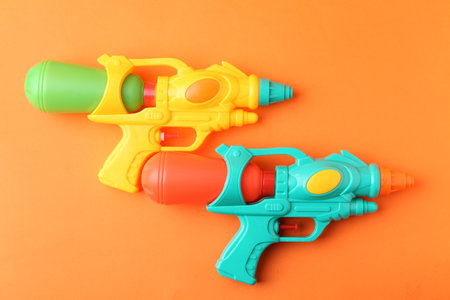 Bright plastic water guns on orange background, top viewの写真素材