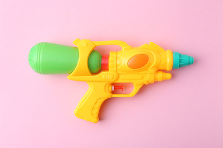 Bright plastic water gun on light pink background, top viewの写真素材