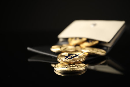 Cryptocurrency. Bitcoins in wallet on black mirror surface, closeup. Space for textの写真素材