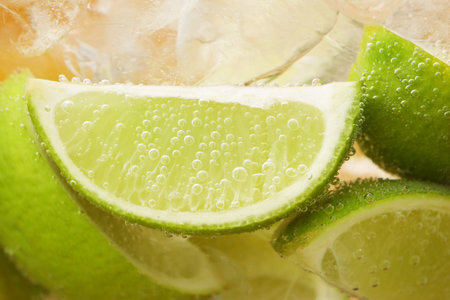 Refreshing soda water with slices of lime and ice in glass on orange background, closeupの写真素材