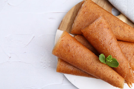 Delicious fruit leather rolls and mint on white table, top view. Space for text