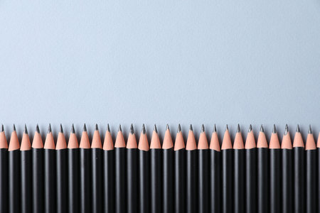 Many sharp graphite pencils on light grey background, flat lay. Space for text