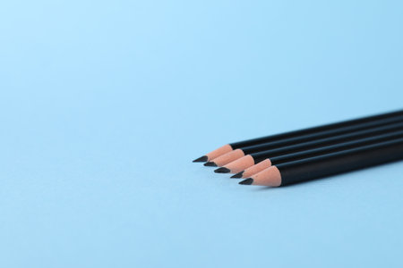 Many sharp graphite pencils on light blue background, closeup. Space for textの写真素材