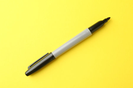 One black marker on yellow background, top viewの写真素材