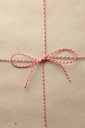 Gift wrapped in kraft paper and bow as background, top view