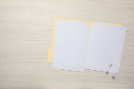 Paper file folder with blank sheets and binder clips on wooden table, flat lay. Space for text