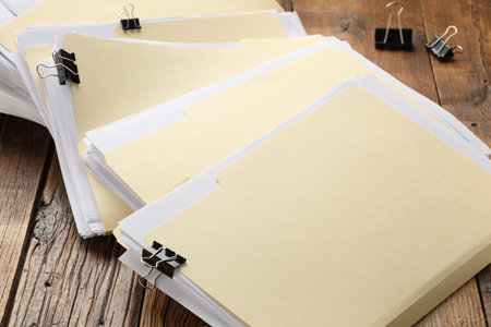 File folders with papers and binder clips on wooden table, closeup