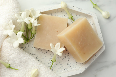 Bars of soap and jasmine flowers on white marble table, flat layの写真素材