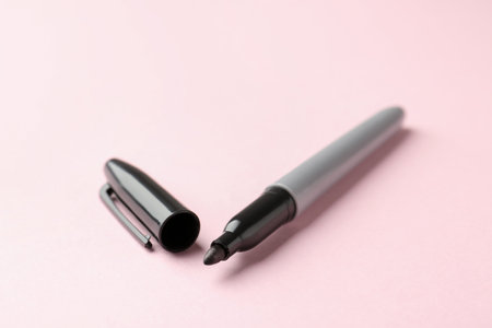One black marker on light pink background, closeup. Space for textの写真素材