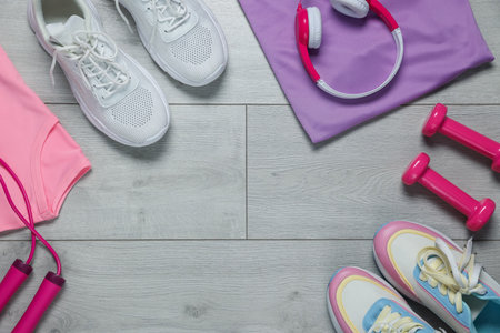 Sportswear, sneakers, skipping rope, headphones and dumbbells on floor, flat lay. Space for textの写真素材