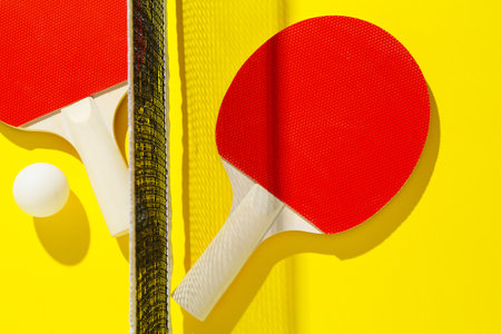 Ping pong rackets, ball and net on yellow background, flat layの写真素材
