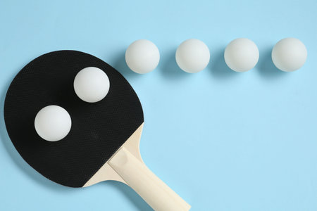 Ping pong racket and balls on light blue background, flat lay
