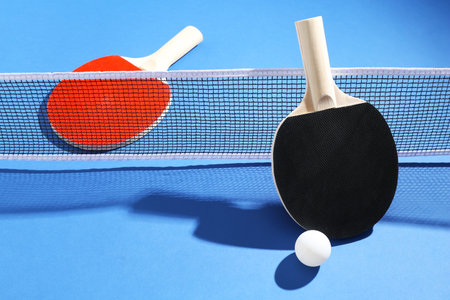Ping pong rackets, ball and net on blue backgroundの写真素材