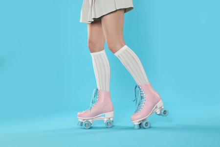 Woman in roller skates on light blue background, closeup
