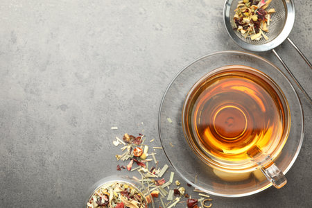 Aromatic herbal tea and dry leaves on grey table, flat lay. Space for textの写真素材