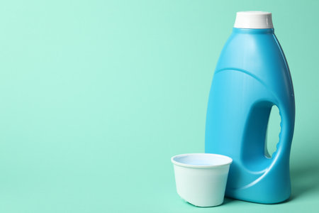 Bottle of fabric softener and cap on turquoise background, space for textの写真素材