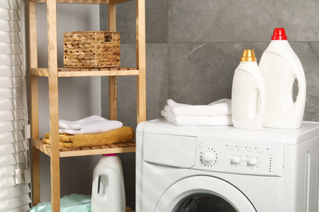 Bottles of fabric softener and towels on washing machine indoorsの写真素材