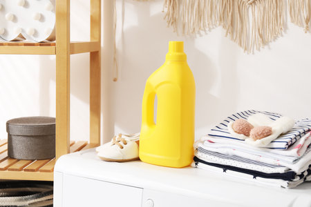 Bottle with fabric softener and baby clothes on washing machine indoorsの写真素材