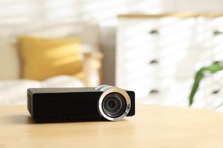 Modern video projector on wooden table indoors. Space for text