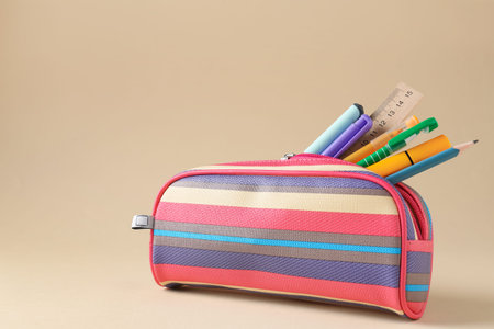 Different stationery in pencil case on beige background. Space for text