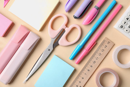 Pens and other stationery on beige background, flat lay