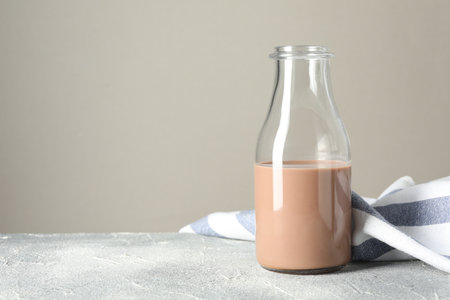 Tasty chocolate milk in glass bottle on grey table, space for textの写真素材