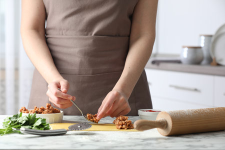 Woman making ravioli bolognese at white marble table, closeupの写真素材