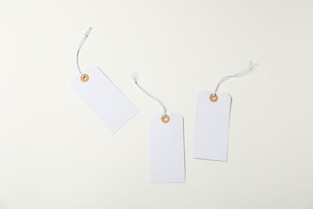 Blank tags with strings on white background, flat lay