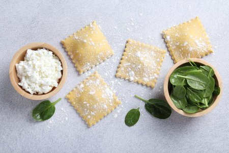 Uncooked ravioli, cottage cheese and spinach on light table, flat layの写真素材