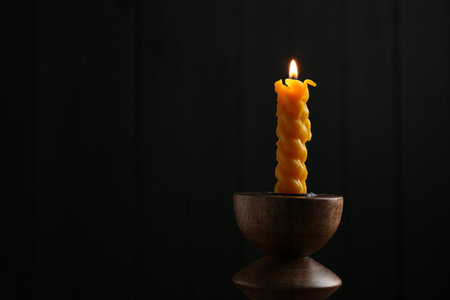 Burning candle in candlestick on mirror surface, space for textの写真素材
