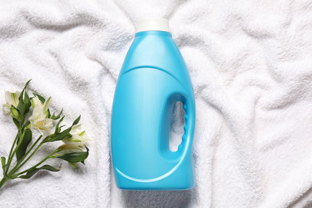 Bottle of fabric softener and flowers on terry towel, flat layの写真素材