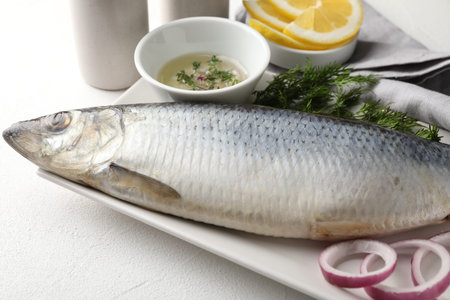 Salted herring and spices on white table, closeup