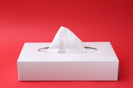 Box with paper handkerchiefs on red background. Space for text