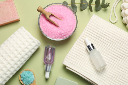 Clean waffle towels and cosmetic products on light green background, flat lay