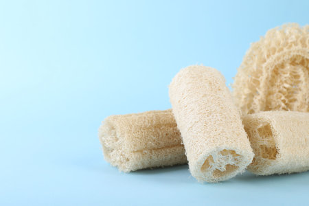 Different loofah sponges on light blue background, closeup. Space for textの写真素材