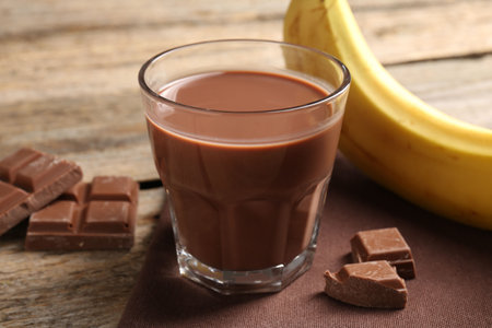 Tasty chocolate milk, pieces and banana on wooden table, closeupの写真素材