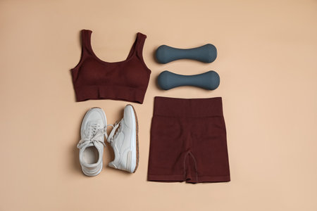Sportswear, dumbbells and sneakers on beige background, flat layの写真素材