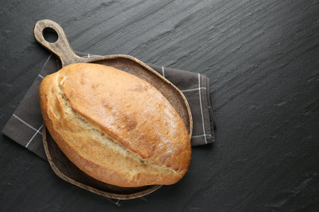 Loaf of bread on black textured table, top view. Space for textの写真素材