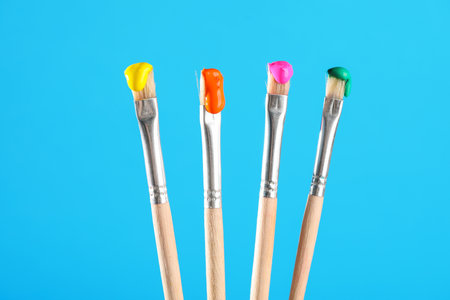 Many brushes with color paints on light blue background, closeupの写真素材