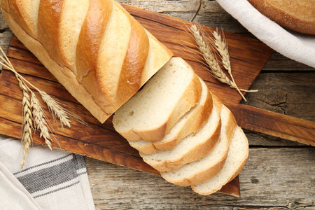 Cut bread loaf and spikes on wooden table, flat lay