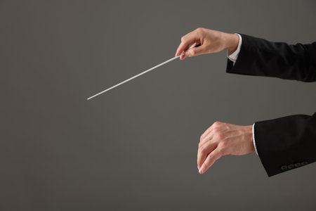Professional conductor with baton on grey background, closeup. Space for textの写真素材