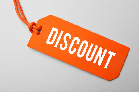 Orange tag with word Discount on light grey background, top viewの写真素材