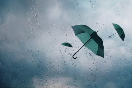 Dark green umbrellas flying in cloudy sky, view through wet window. Stormy weatherの写真素材