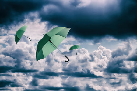 Green umbrellas flying in cloudy sky. Stormy weatherの写真素材
