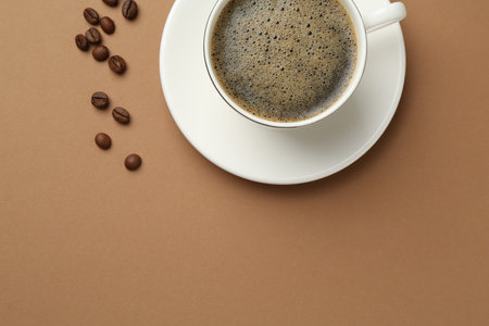 Aromatic coffee in cup and beans on beige background, flat lay. Space for textの写真素材
