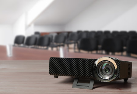 Modern video projector on wooden table in conference roomの写真素材