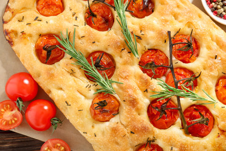 Delicious focaccia with tomatoes and spices on table, flat layの写真素材