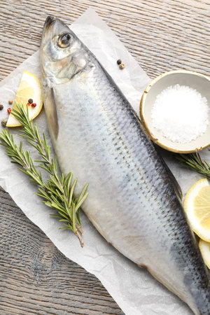 Salted herring and spices on wooden table, flat lay