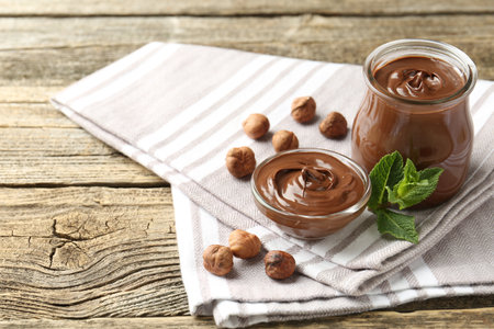 Tasty chocolate spread, hazelnuts and mint on wooden table, closeupの写真素材