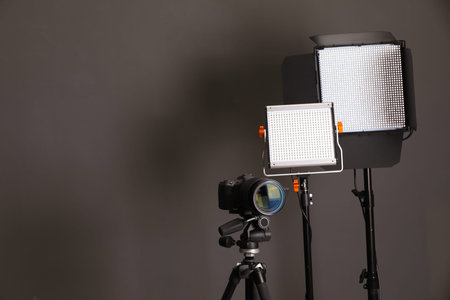 Professional lighting equipment and camera on grey background. Space for text